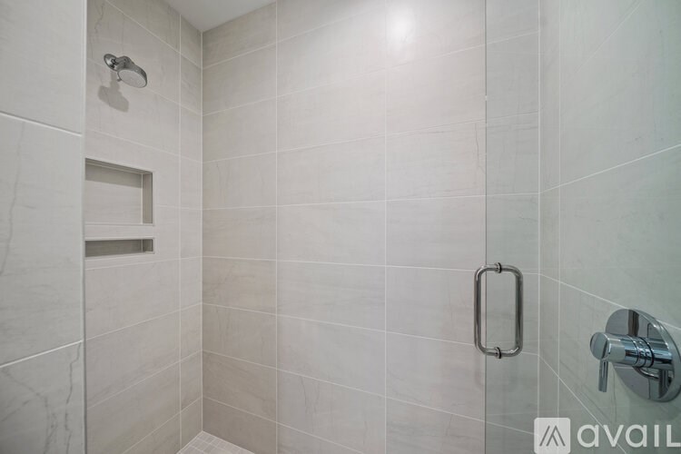 A shower area with a glass door and a chrome handle.