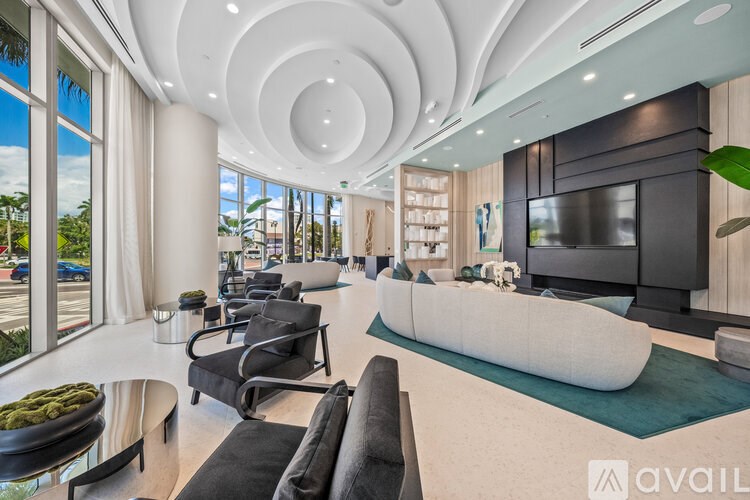 A modern living room with a curved ceiling and a large window overlooking a parking lot.