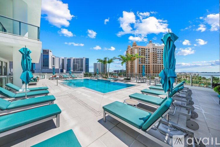 A pool area with sun loungers and a view of the city.