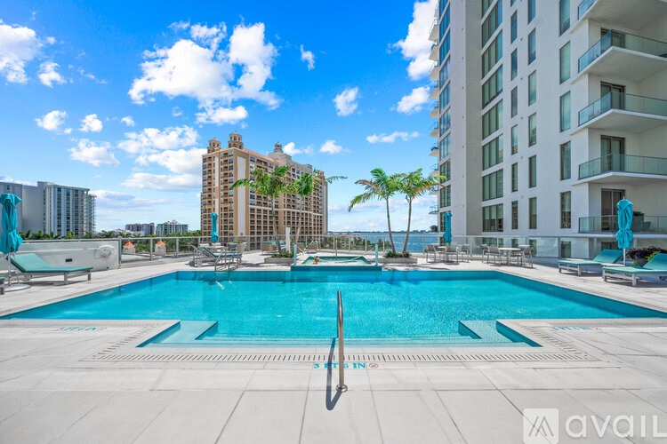 A large swimming pool in front of a tall building with a palm tree.