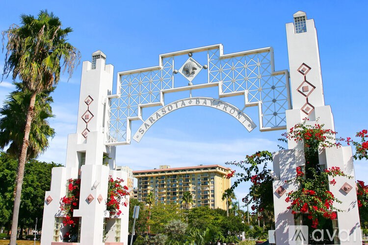 A white archway with red flowers and a blue sky in the background.