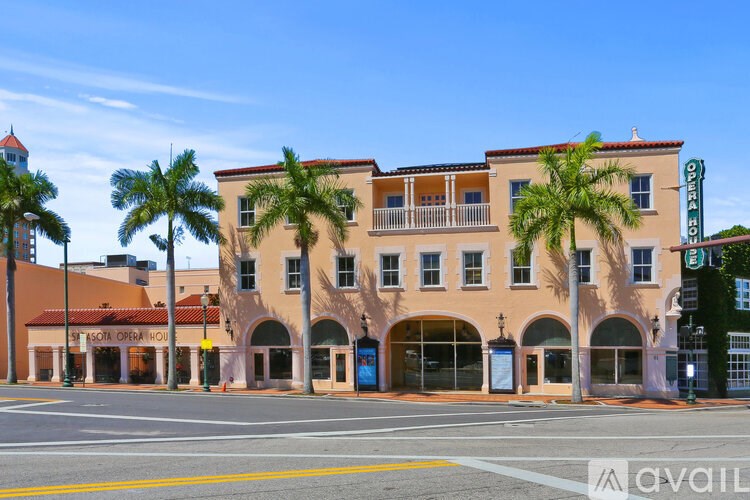 A building with a red roof and palm trees in front.