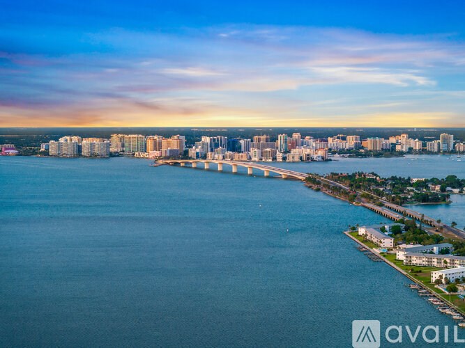 A cityscape with a body of water in the foreground and a bridge connecting two land masses.