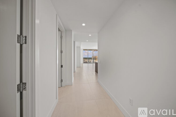 A long, narrow hallway with white walls and a tiled floor.