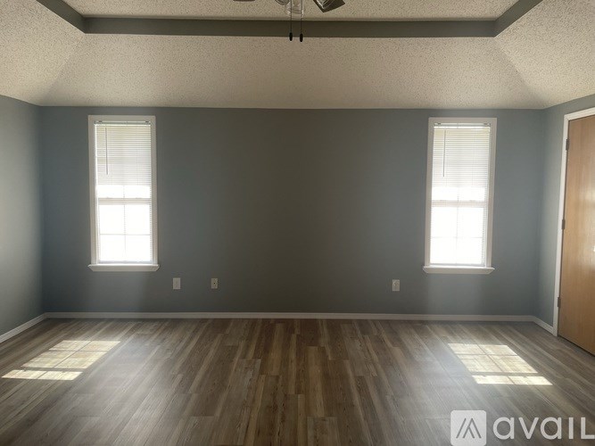 A room with wooden floors and two windows.