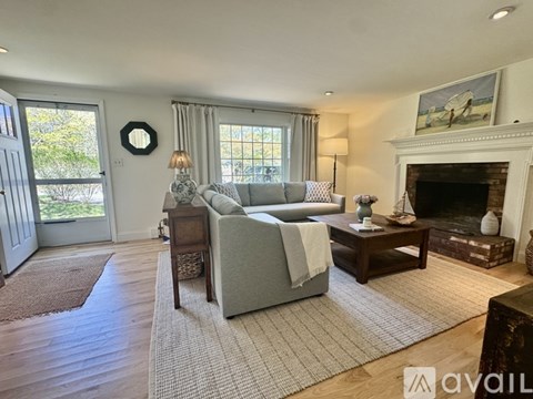 A living room with a grey couch, a fireplace, and a painting on the wall.