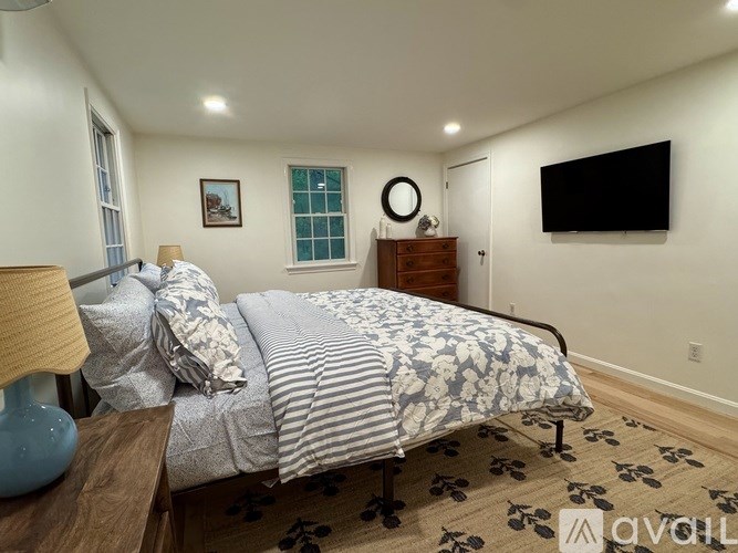 A bedroom with a bed, a lamp, a dresser, and a television.