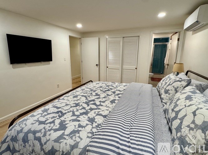 A bedroom with a large bed and a flat screen TV mounted on the wall.