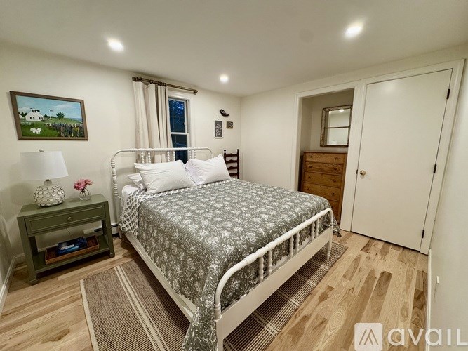 A bedroom with a bed, nightstand, and a painting on the wall.