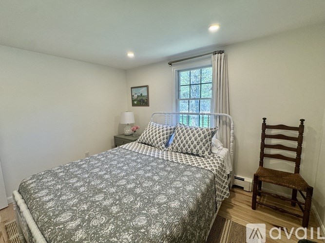 A bedroom with a bed, chair, and window.