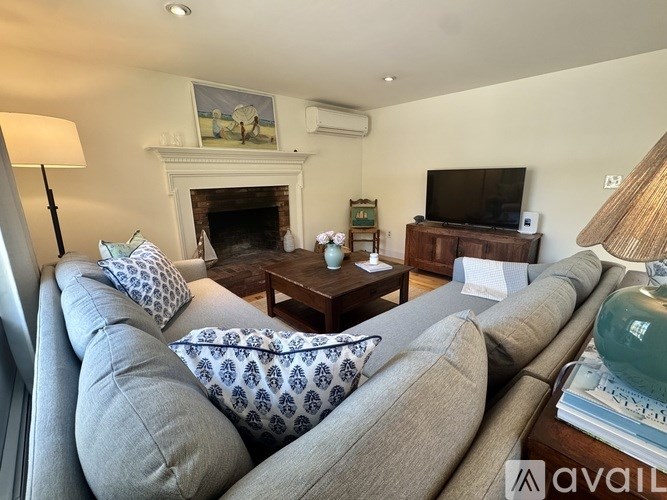 A living room with a grey sofa and a fireplace.