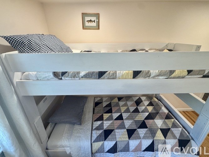 A white bunk bed with a black and white checkered patterned mattress pad.