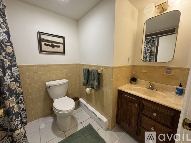 A bathroom with a toilet, sink, and mirror.