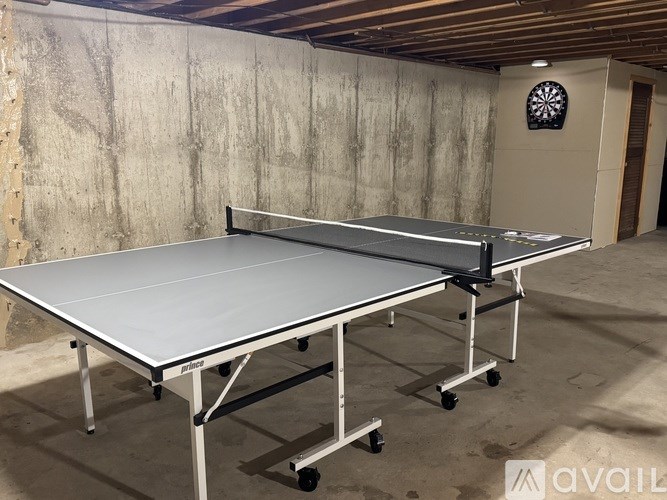 Two ping pong tables are set up in a room with concrete walls.