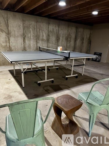 A ping pong table with a green chair and a wooden stool in front of it.