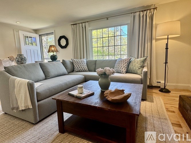 A living room with a grey couch, a wooden coffee table, and a lamp.