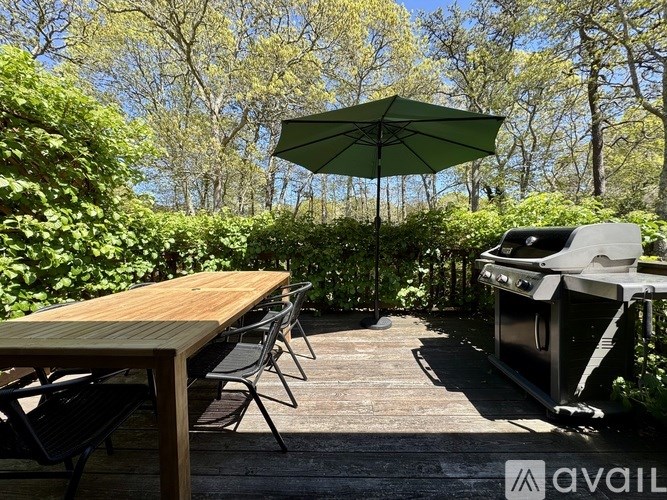 A wooden table is set up under a green umbrella on a wooden deck.