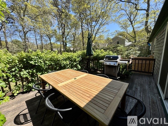 A wooden table is on a deck with a chair and a table umbrella.
