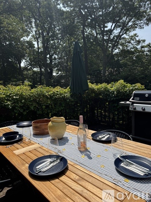 A table set for a meal with a bottle of wine and a vase on it.