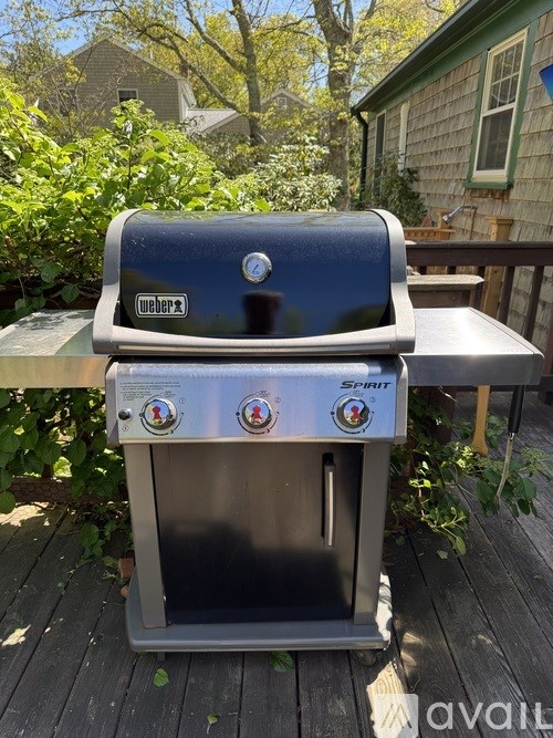 A Weber Smoky grill is on a wooden deck.