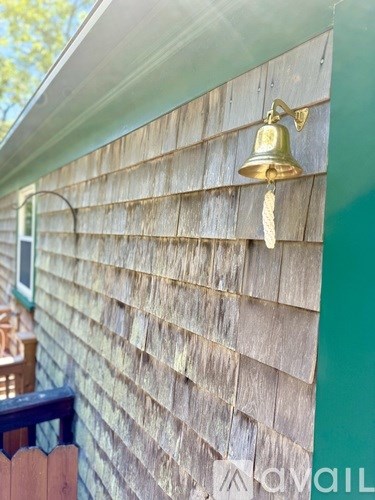 A golden bell hangs on a green wall.