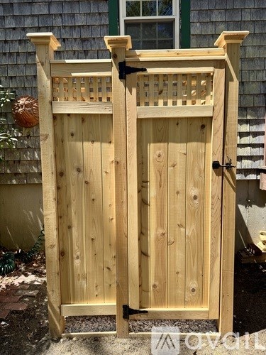 A wooden gate with a black latch stands in front of a house.
