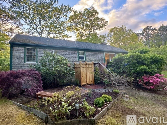 A house with a wooden door and windows surrounded by a garden.