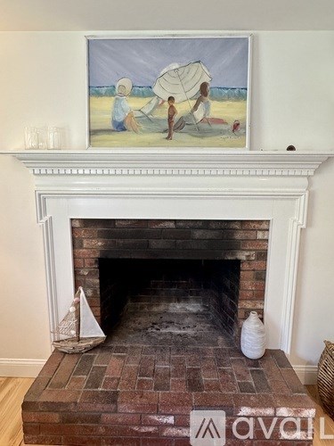 A painting of two people fishing is hanging above a fireplace.