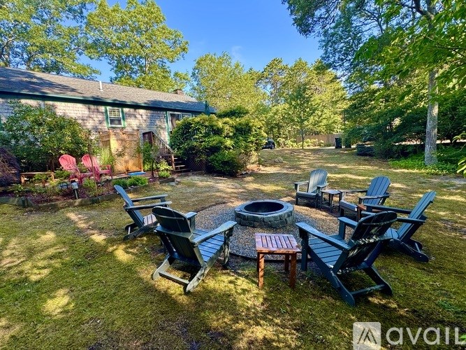 A backyard with a fire pit and chairs.