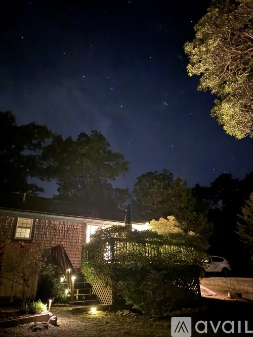 A nighttime view of a house with a car parked in the driveway.