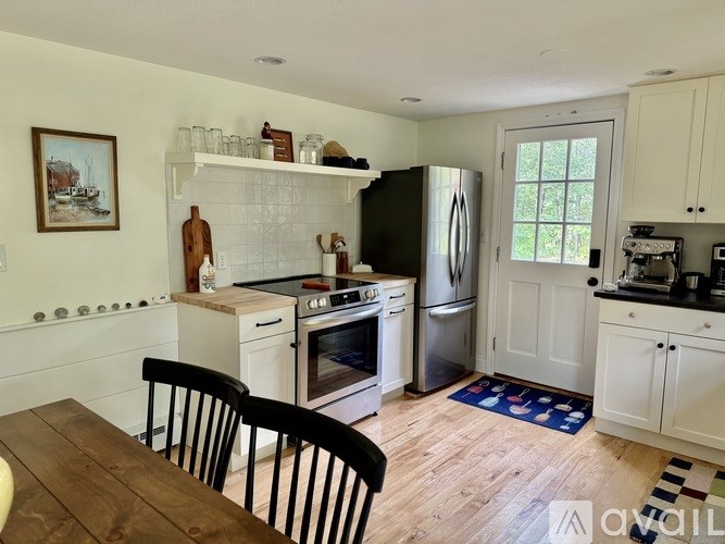 A kitchen with a black fridge and white cabinets.