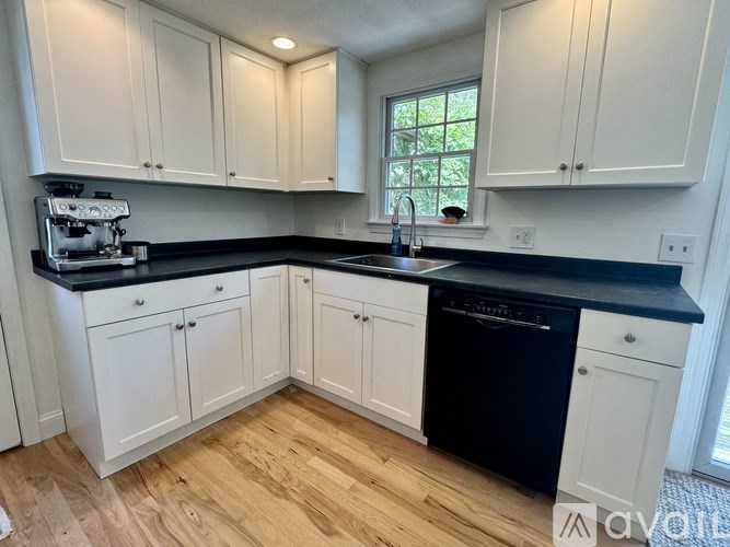 A kitchen with white cabinets and black countertops.