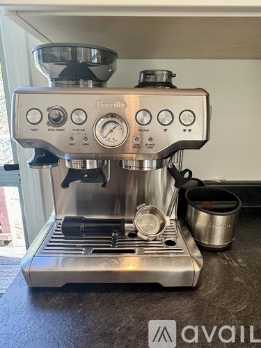 A shiny silver espresso machine with a glass carafe on top and a metal cup on the side.