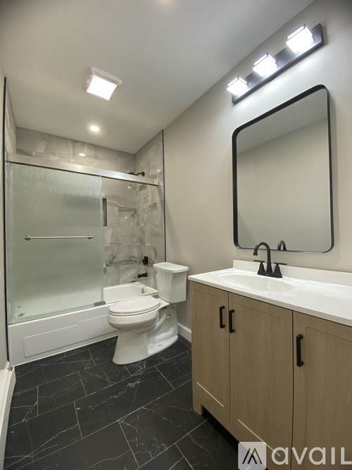 A bathroom with a toilet, sink, and mirror.