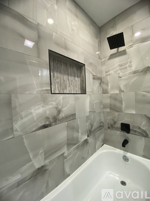 A bathroom with a white tub and a mirror above it.