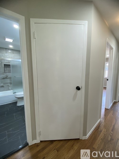 A white door in a room with wooden floors and a grey wall.