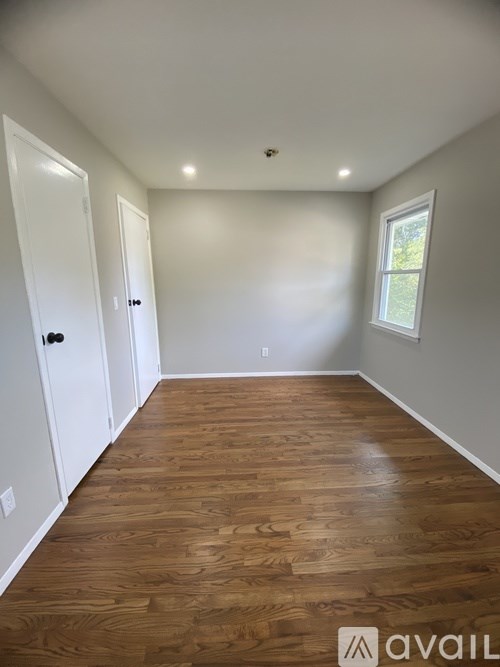 A room with wooden flooring and white walls.