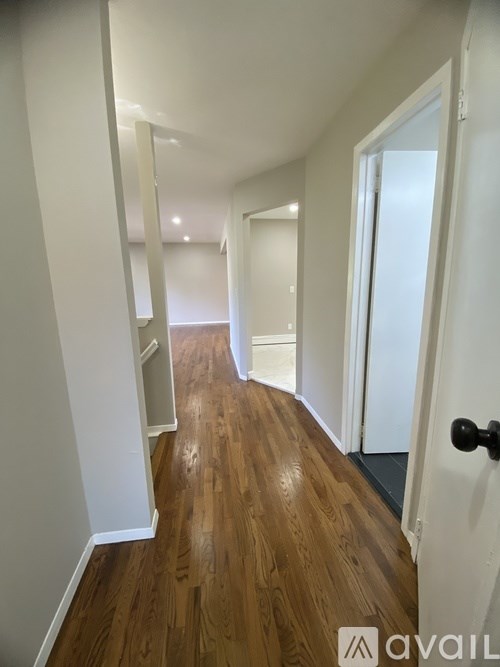 A hallway with wood floors and white walls.