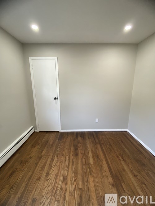 A room with a white door and wooden flooring.