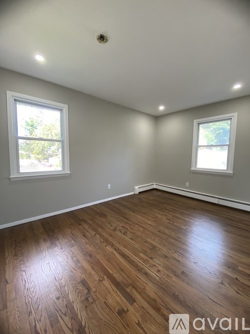 A room with wooden floors and two windows.