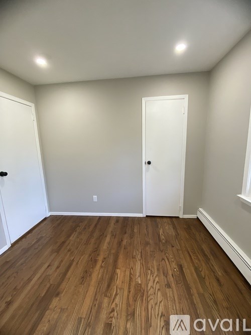 A room with wooden floors and two white doors.
