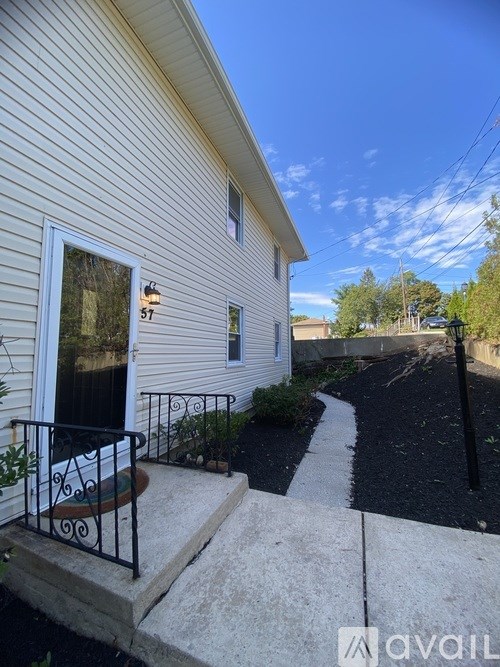 A house numbered 57 with a black metal railing on the front porch.