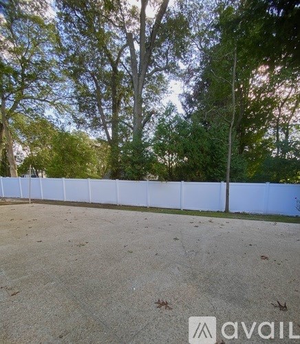 A white fence in a yard with trees in the background.