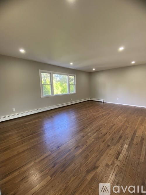 A room with wooden flooring and a window letting in natural light.