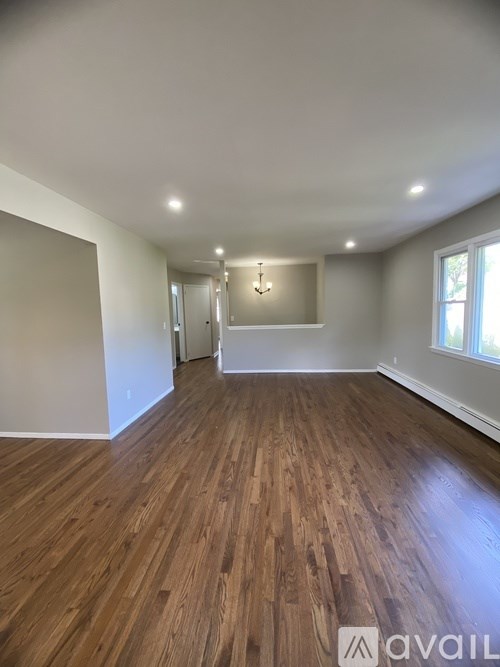 A room with wooden flooring and a window on the right side.