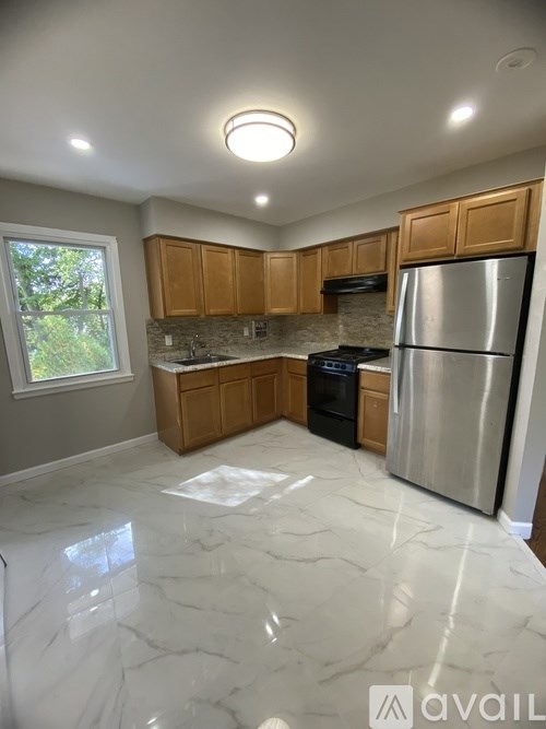 A kitchen with a marble floor and wooden cabinets.