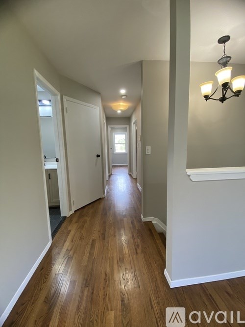 A hallway with wood floors and white walls.