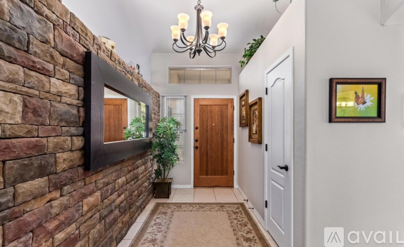 A hallway with a brick wall and a chandelier.