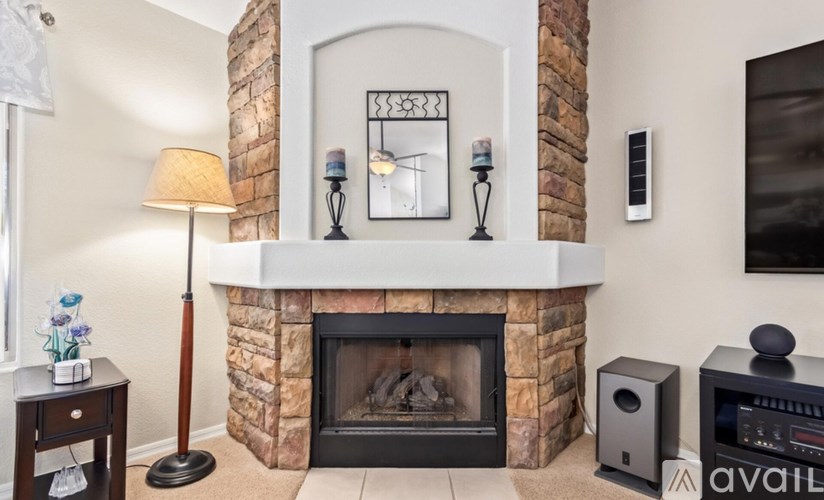 A living room with a fireplace, a lamp, and a speaker.