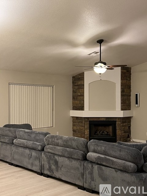 A grey couch in a living room with a fireplace and a fan.